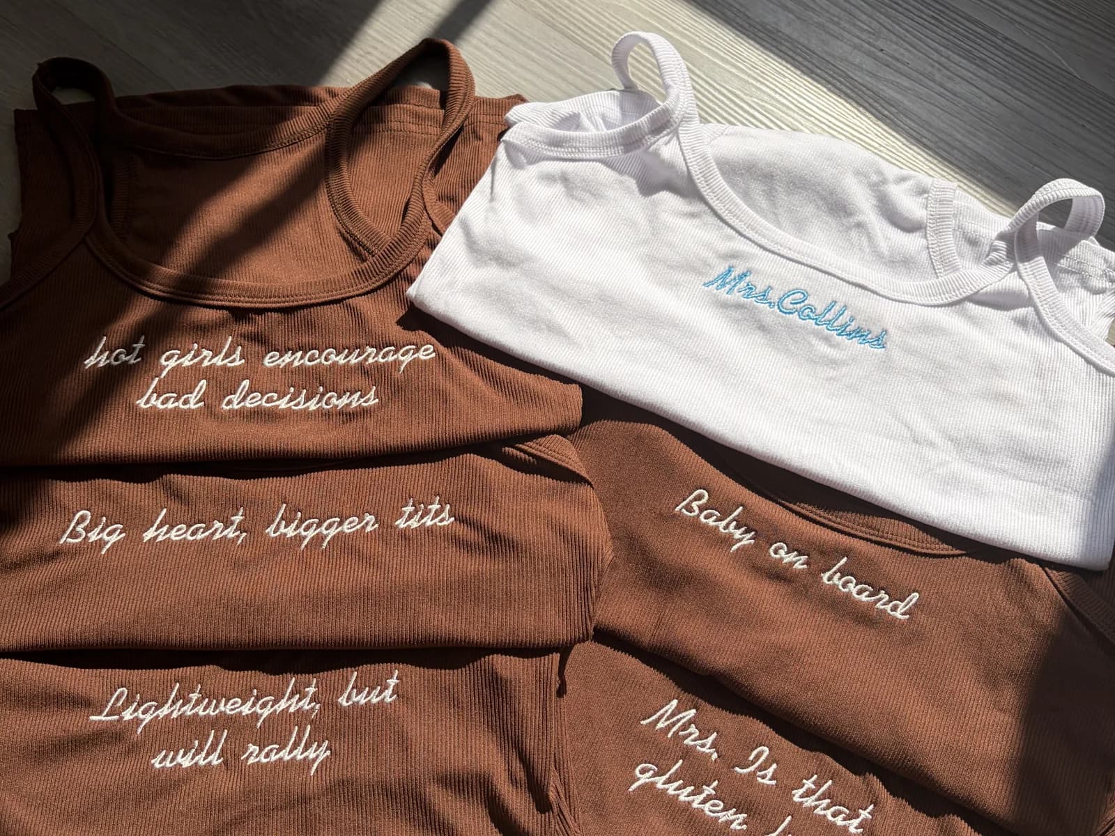 Custom embroidered tank tops arranged together in warm sunlight