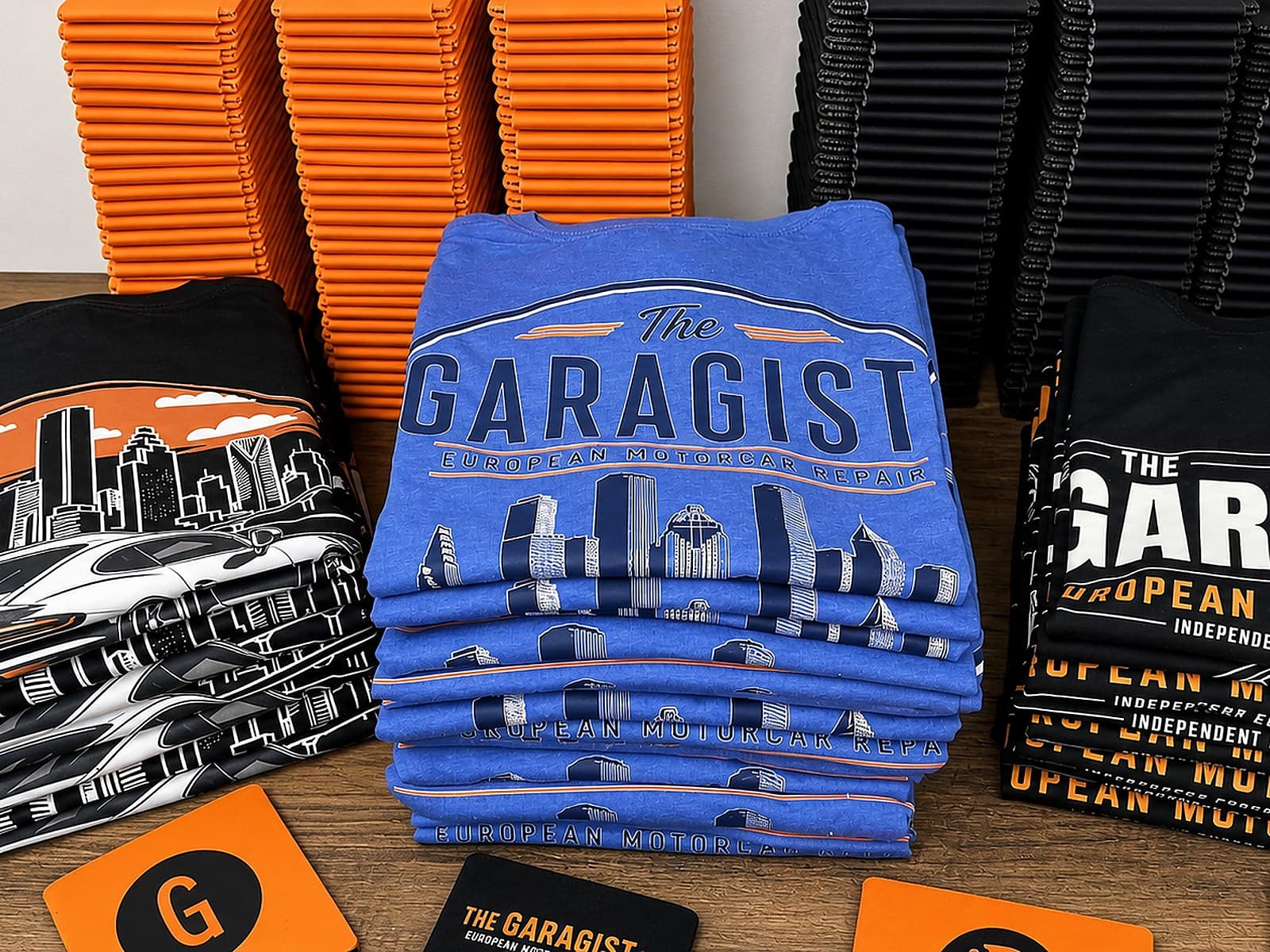 Garagisti shirts, koozies, stickers, and branded cards arranged on a table