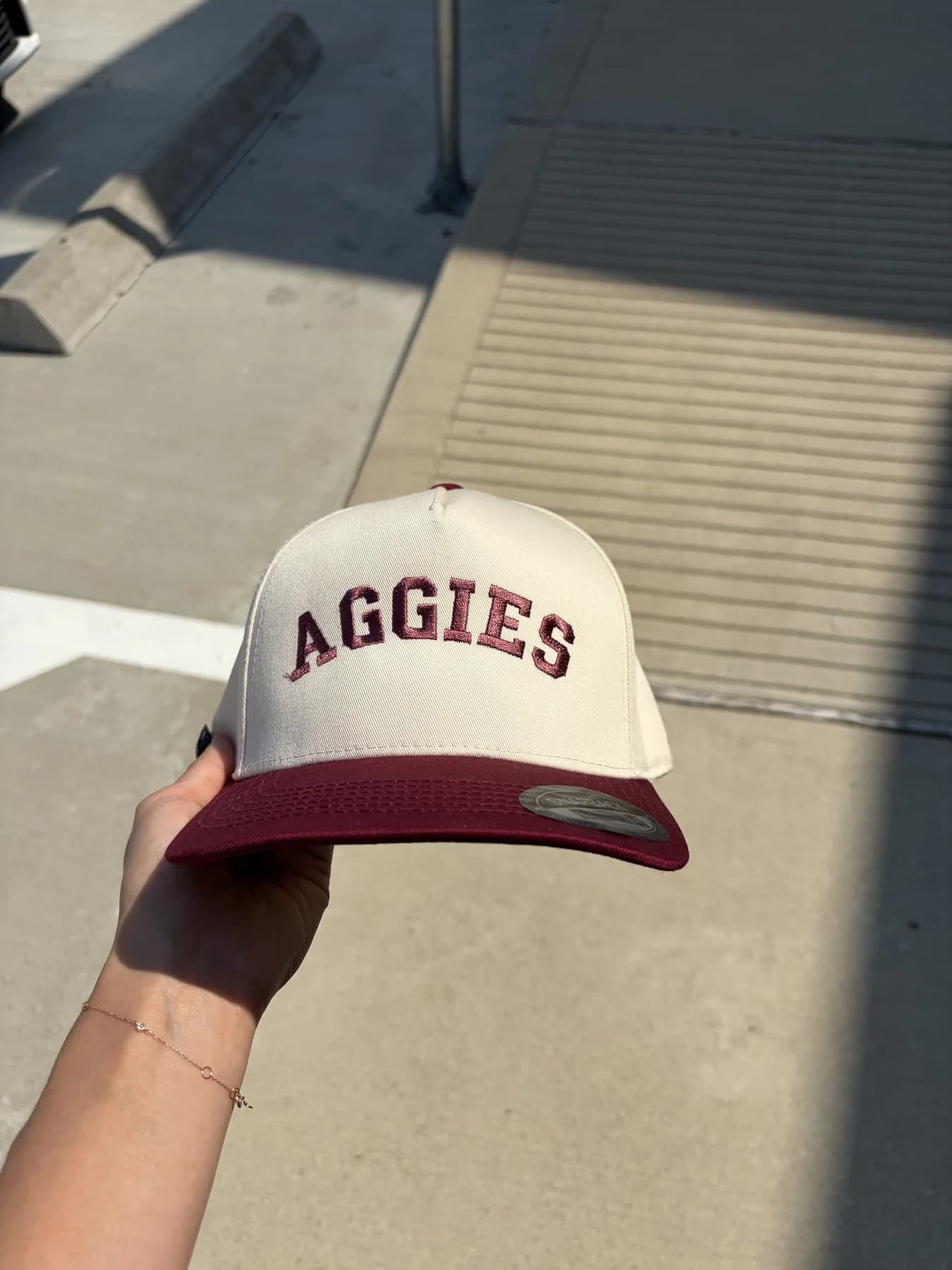 Cream and maroon custom Aggies trucker hat held outdoors