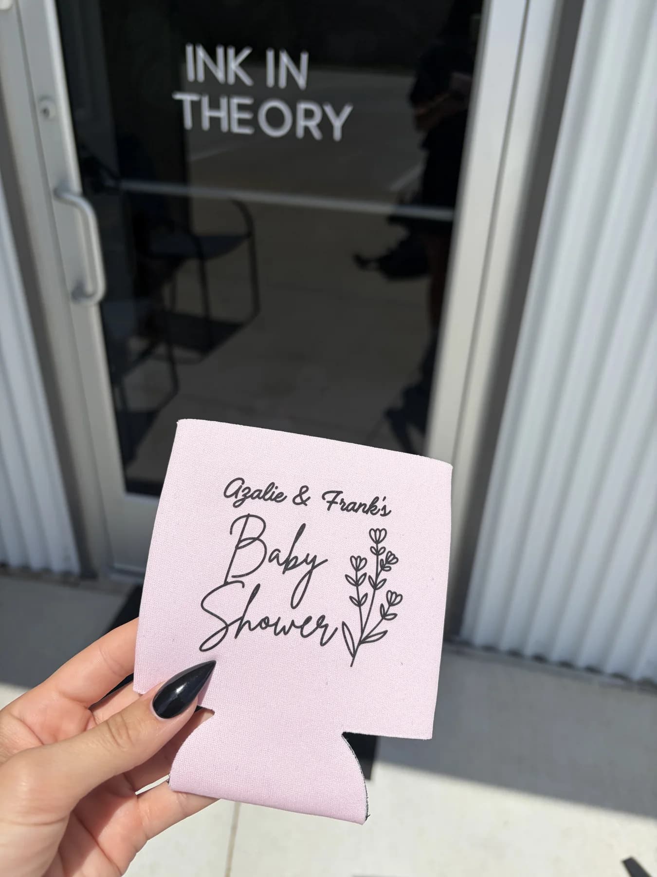 Pink custom baby shower koozie held outside the Ink In Theory studio