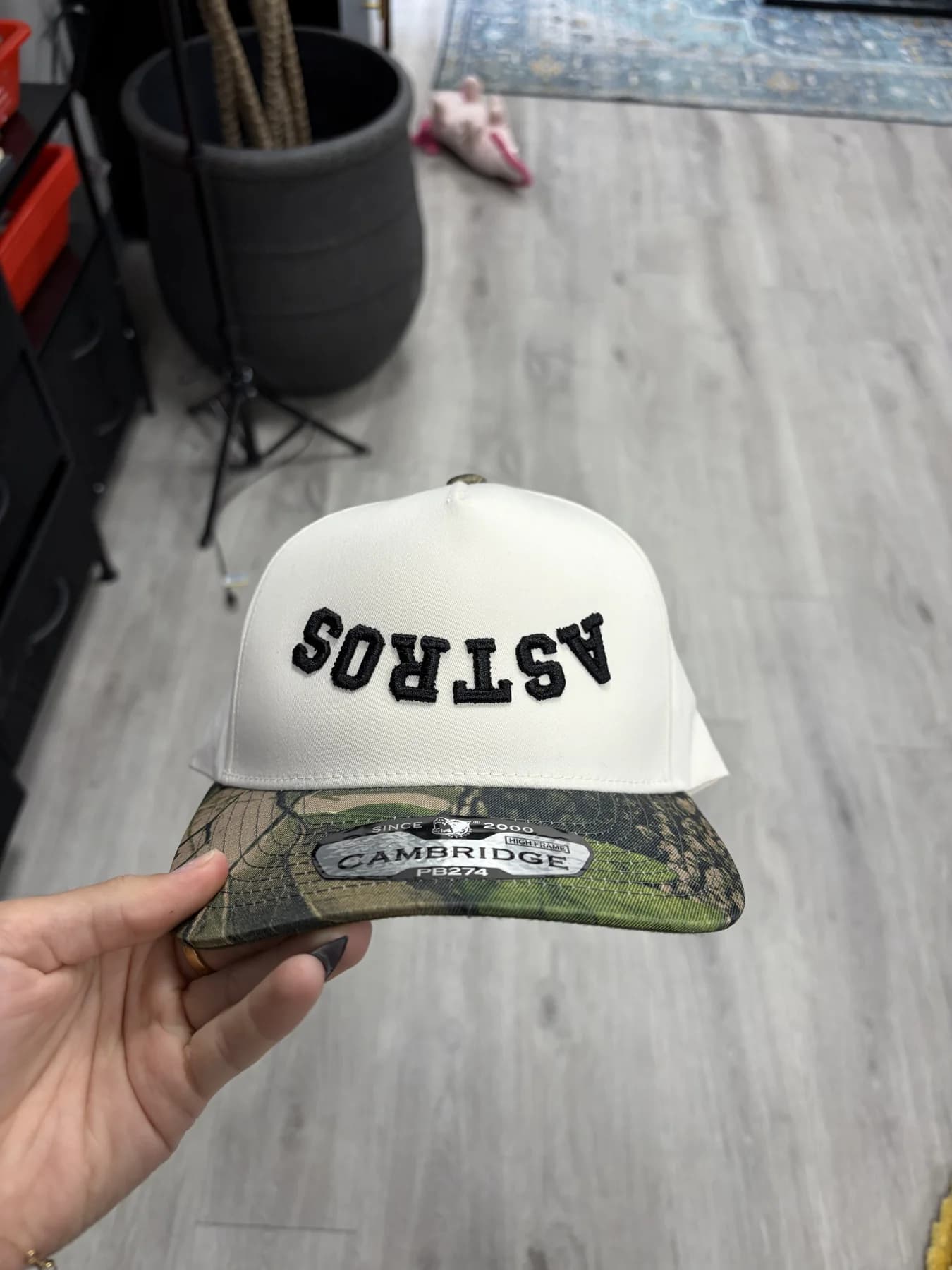 Cream and camouflage custom trucker hat held indoors