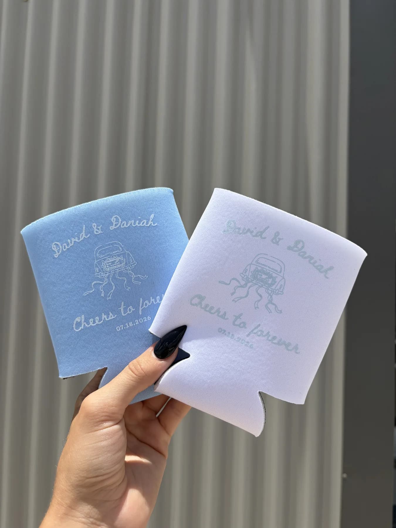 Two pastel custom event koozies held in sunlight